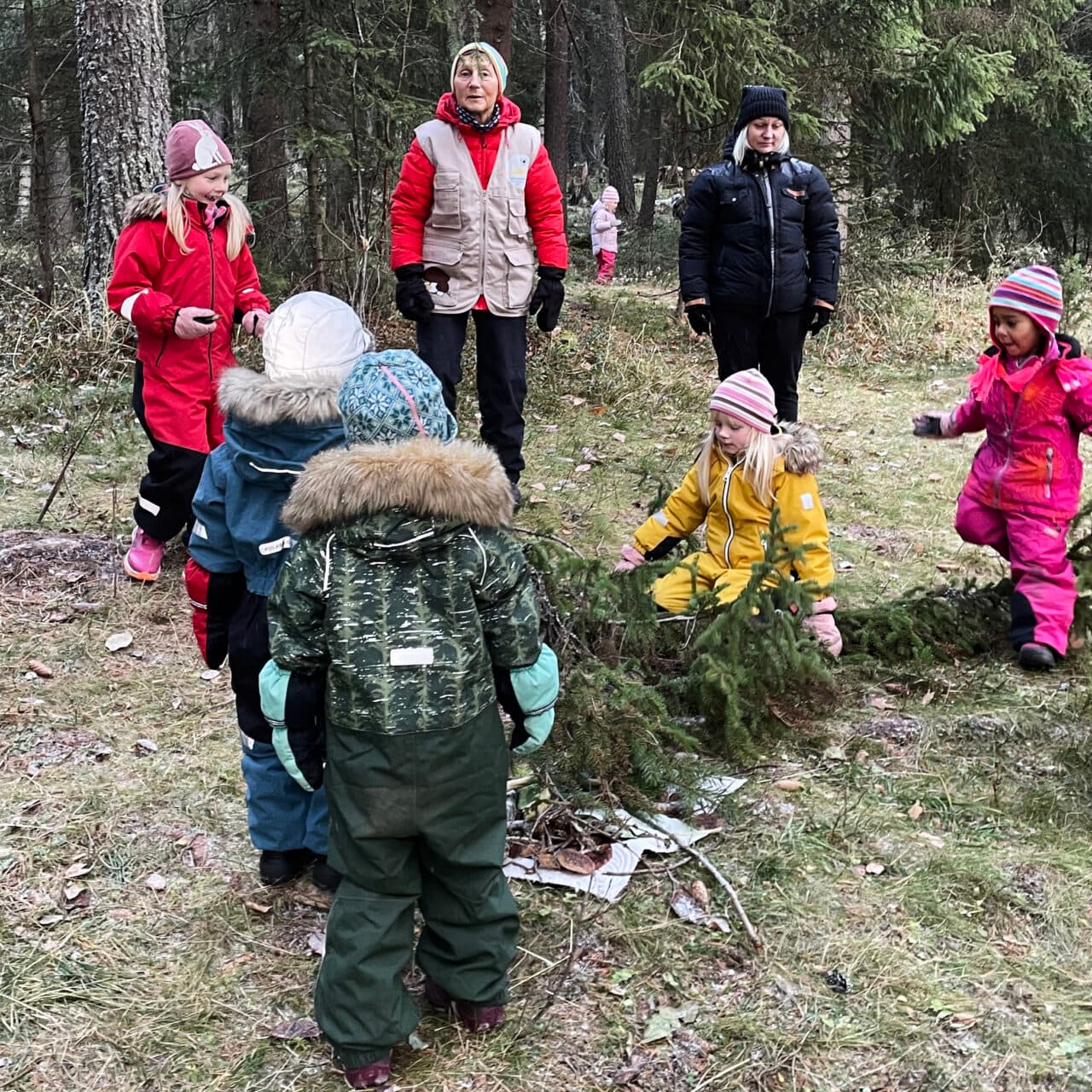 Vuxna och barn som leker i skogen
