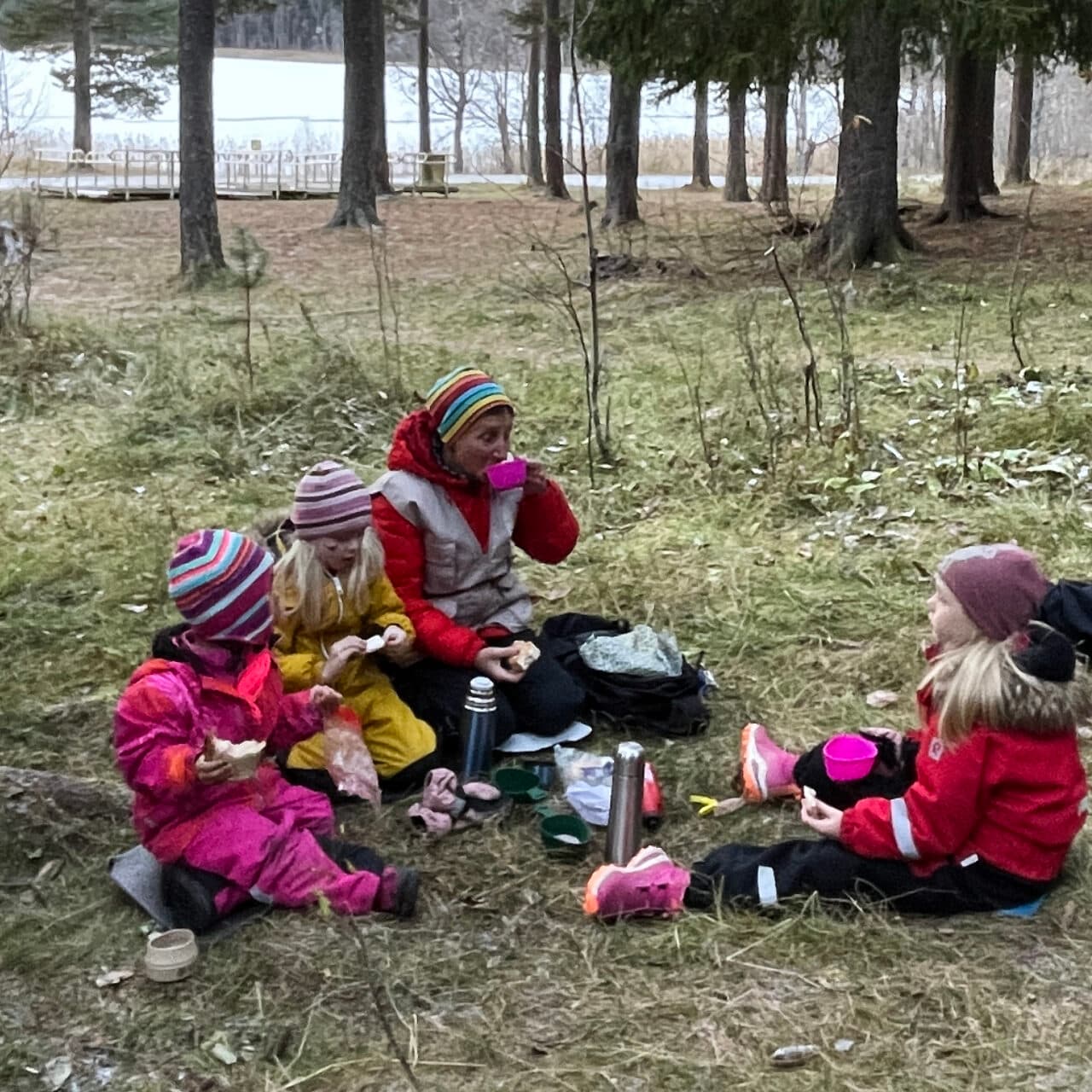 Vuxna och barn som fikar i skogen