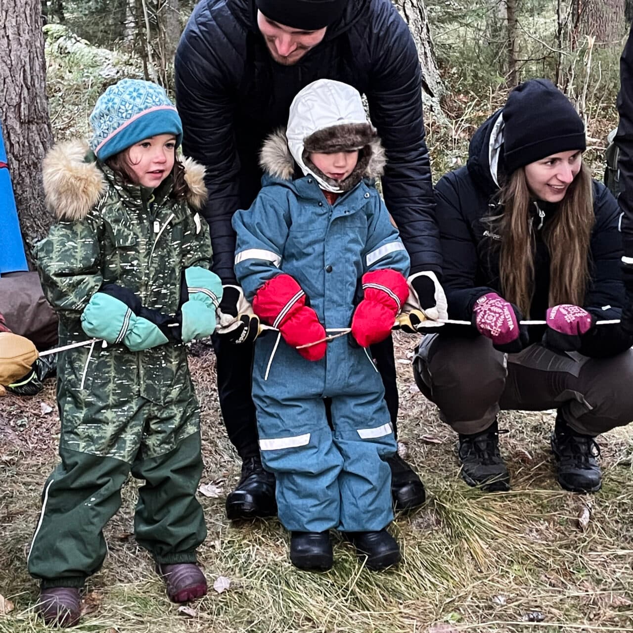 Vuxna och barn som leker i skogen