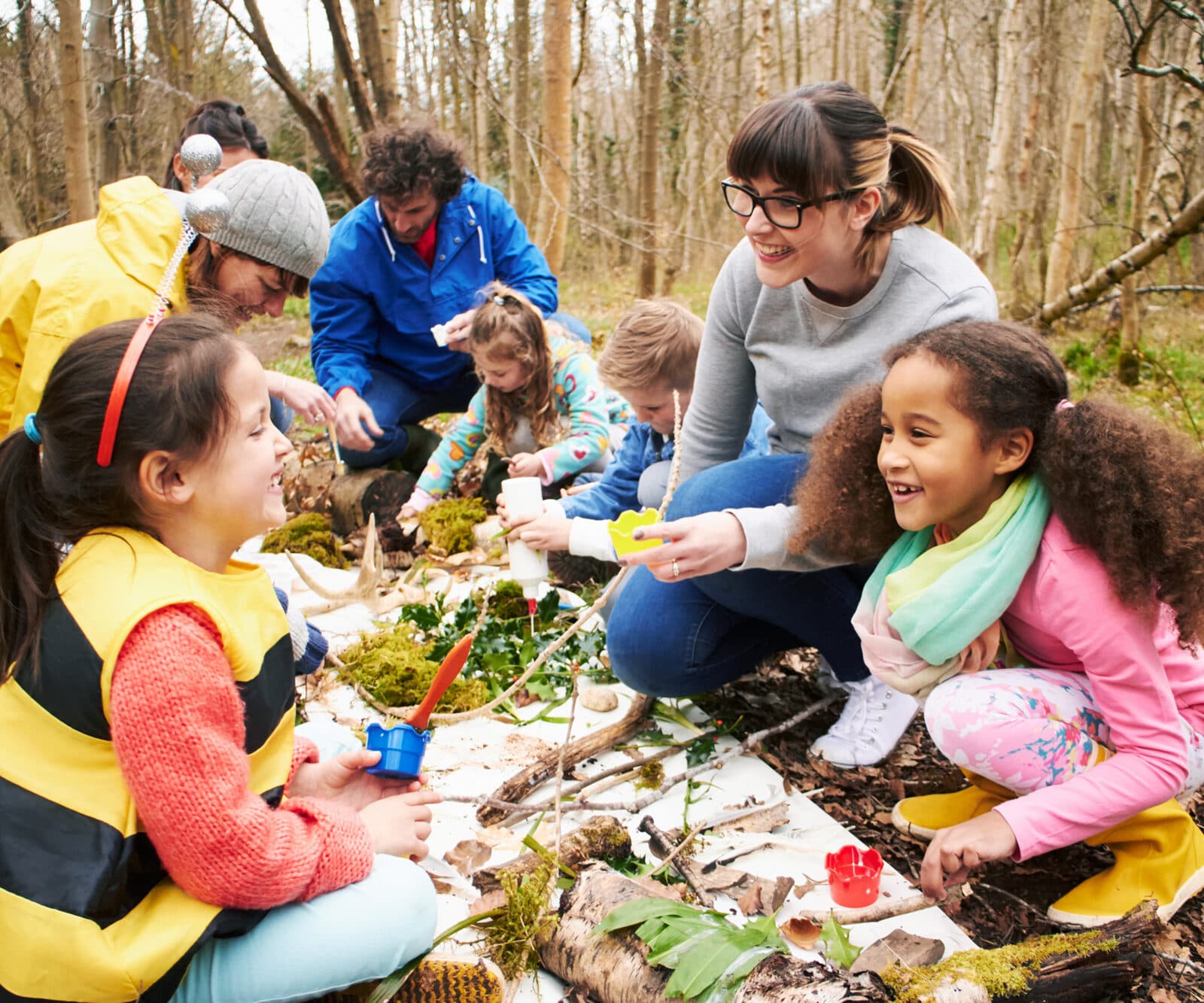 Vuxna och barn som leker i skogen